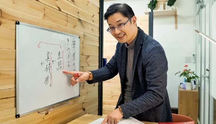 ホワイトボードに指を指し説明をする塾長